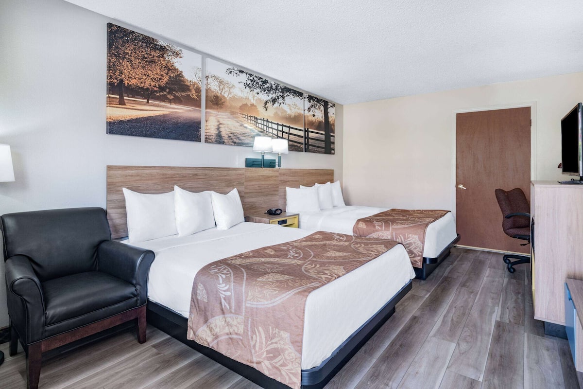 Ein Hotelzimmer mit zwei Betten, einem Schreibtisch, einem Stuhl und einem Fernseher.