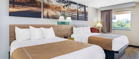 A hotel room with two beds, a large window with curtains, and artwork on the wall.