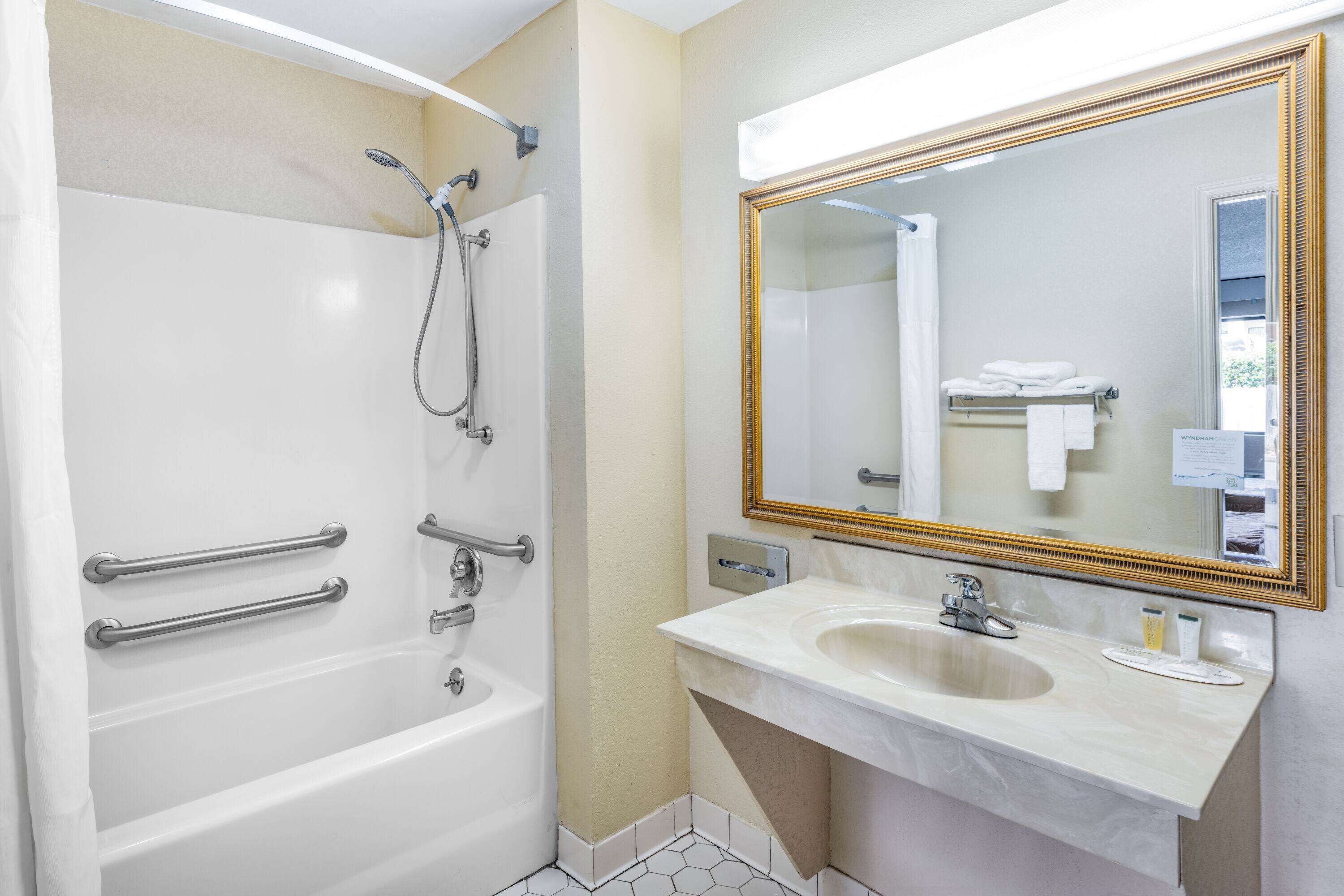 A bathroom with a bathtub, a sink, a mirror, and a shower.