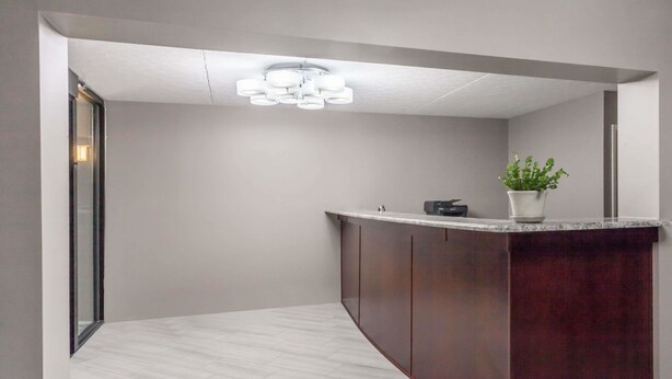 A modern reception area with a marble counter, dark wooden cabinets, and a ceiling light fixture. - Days Inn by Wyndham Nashville Saint Thomas West Hospital (Nashville)