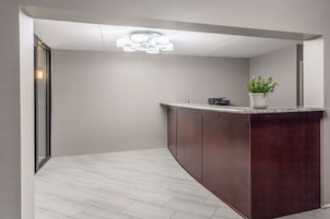 A modern reception area with a marble counter, dark wooden cabinets, and a ceiling light fixture.