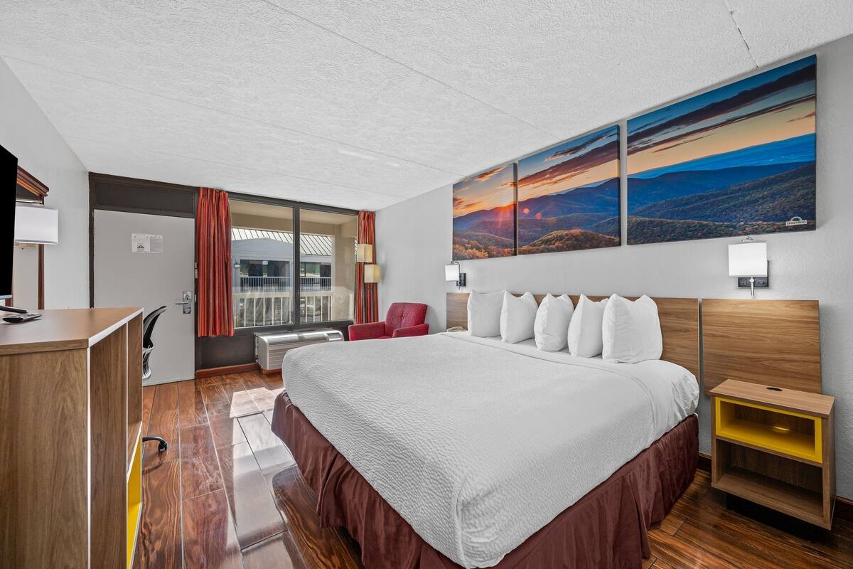 Une chambre d’hôtel avec un grand lit, un bureau, une chaise et une fenêtre avec des rideaux.