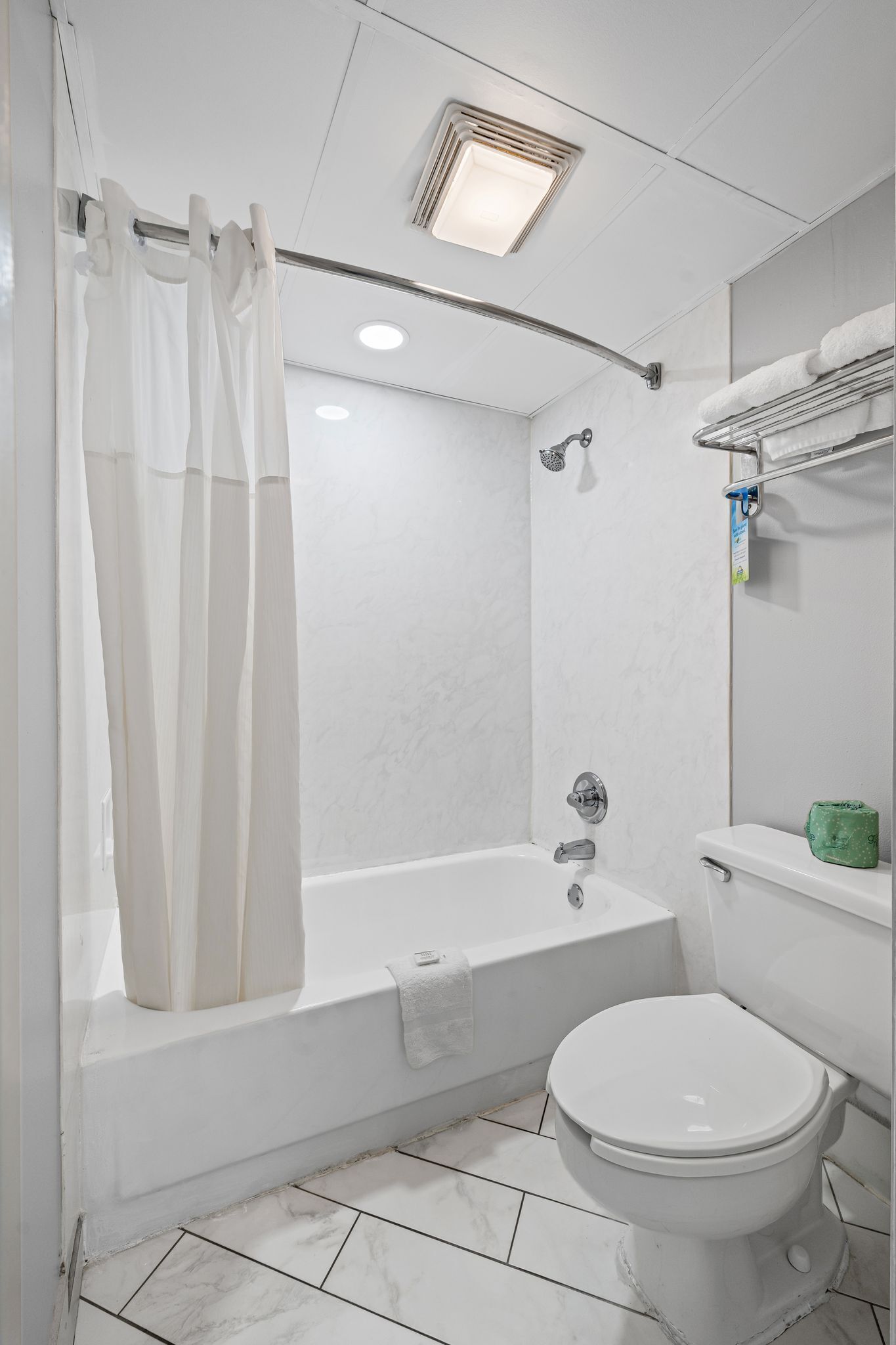 A modern bathroom with a bathtub, toilet, and shower curtain.