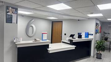 A reception area with a desk, a phone, a sign, and a door.