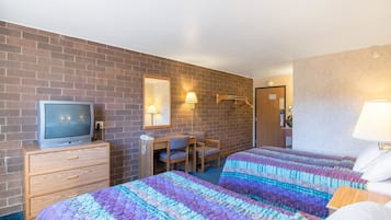 A hotel room with two beds, a desk, a chair, a television, and a mirror.