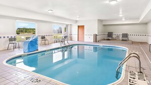 An indoor swimming pool with clear blue water, a tiled deck, and a view of a park through a large window. - Spark by Hilton Springfield Southwest (Springfield)