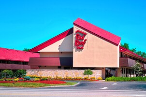 A Red Roof Inn with a red roof and beige walls, surrounded by a landscaped garden with colorful flowers.
