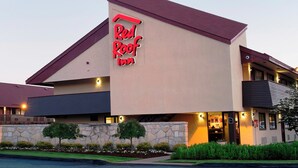 Un hôtel Red Roof Inn avec une façade en pierre, un toit plat et une entrée bien éclairée.