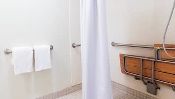 A bathroom with a shower curtain, a grab bar, and two towels on a rack.