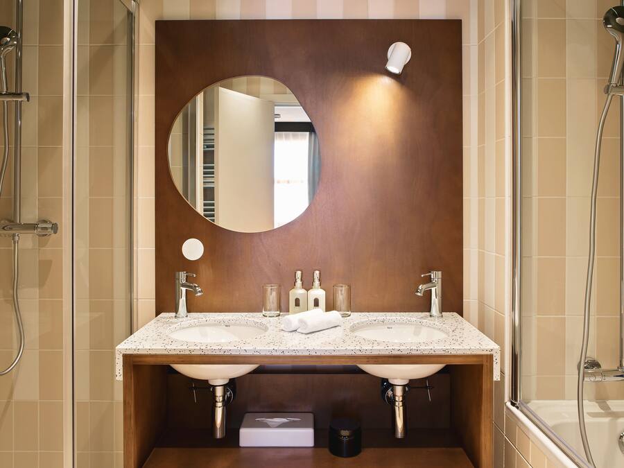 A bathroom with a double sink, a mirror, and a shower.