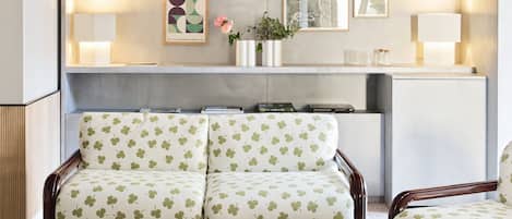 Una sala de estar moderna con un sofá y sillones, una mesita de centro y una estantería con libros y objetos decorativos.