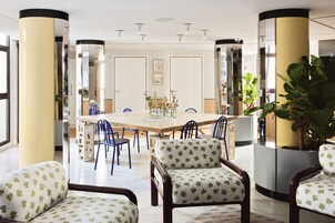 A modern dining area with a large table, blue chairs, and a central floral arrangement.