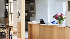 Ein moderner Empfangsbereich mit einem Holztisch, einem Laptop und einer Blumenvase.