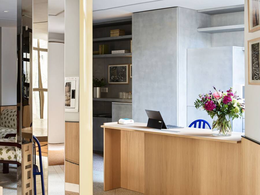 Un'accoglienza moderna con una scrivania in legno, un laptop e un vaso di fiori.