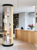 A modern reception area with a wooden desk, a laptop, and a vase of flowers.