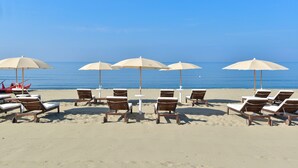 Ein Strand mit weißen Sonnenschirmen und Holzliegen.