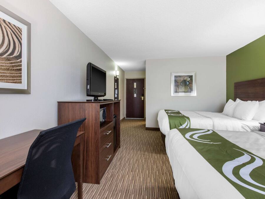 Una habitación de hotel con cama, escritorio, televisor y una silla.