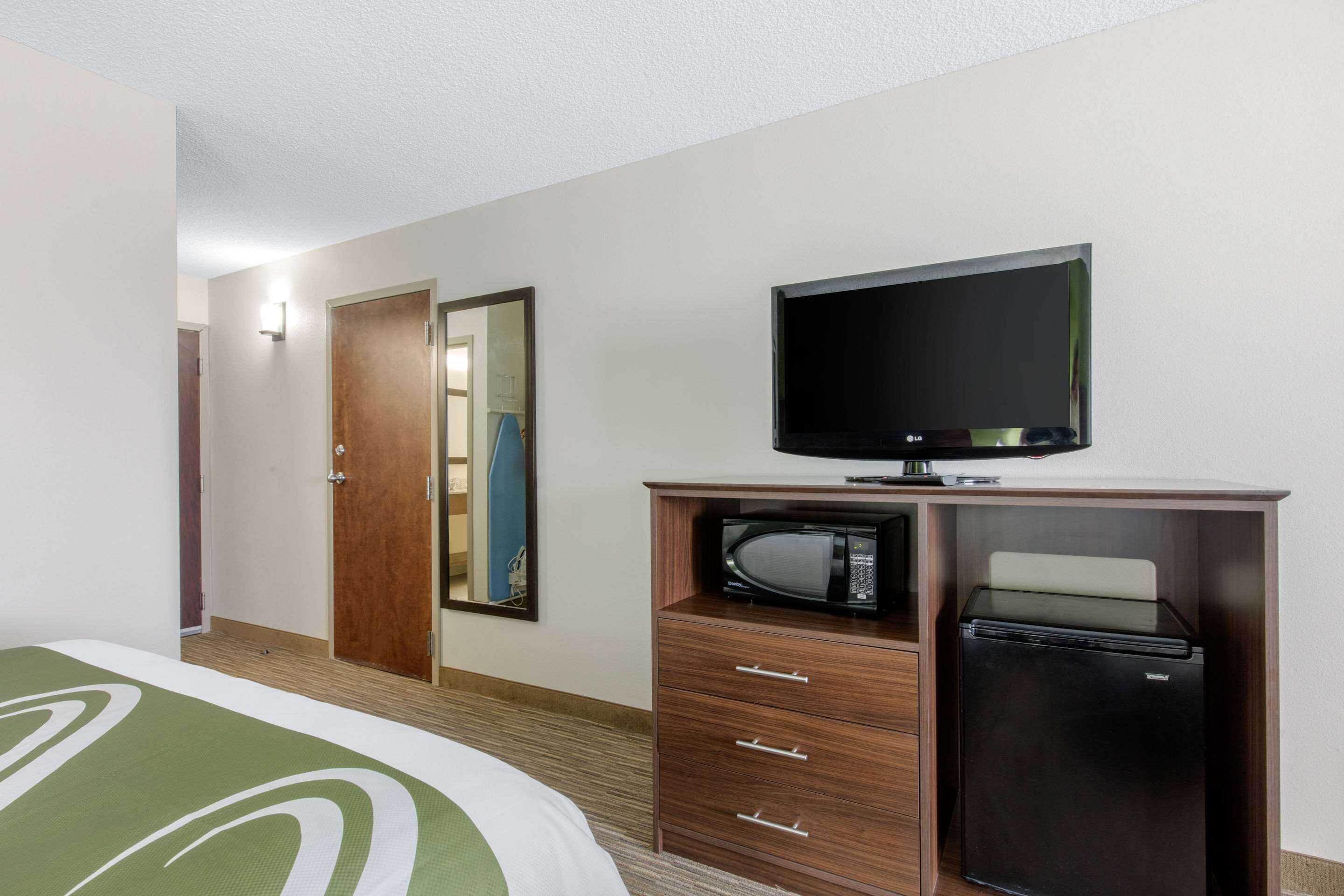 Une chambre d’hôtel équipée d’un lit, d’une télévision, d’un four à micro-ondes et d’un réfrigérateur.