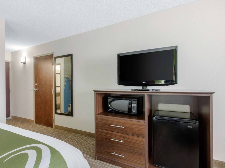 Habitación de hotel con cama, televisión, microondas y refrigerador.