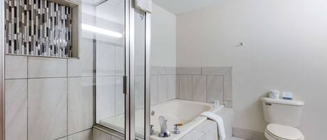A modern bathroom with a glass shower enclosure, a freestanding bathtub, and a toilet.