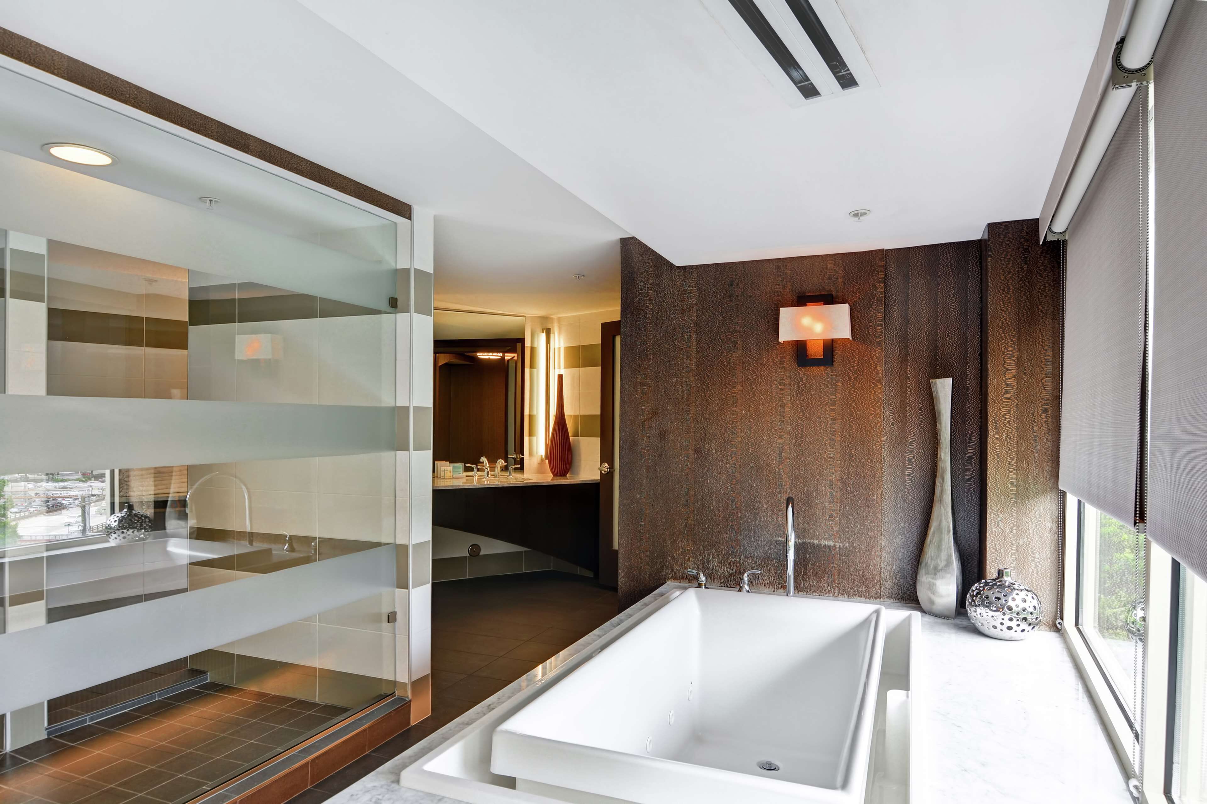 Een moderne badkamer met een douchecabine van glas, een ruim bad en een wastafel met spiegel.