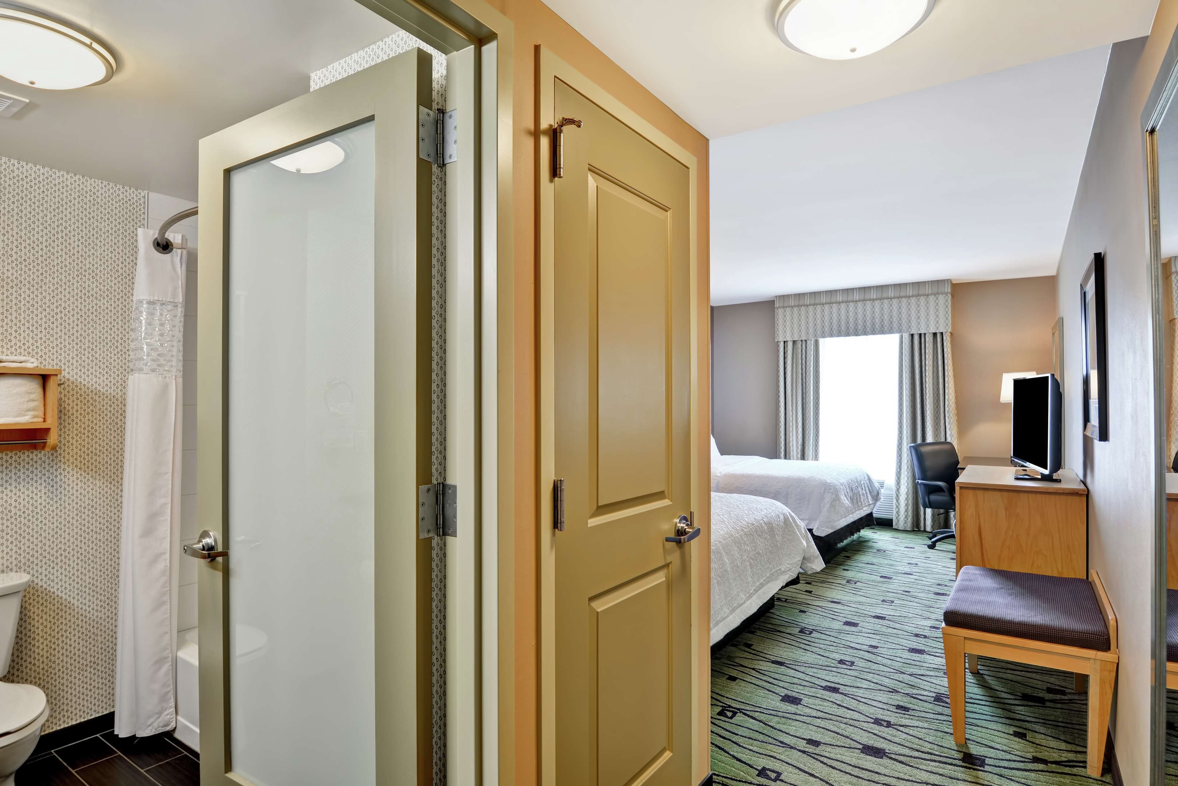 A hotel room with a bed, a desk, a chair, a television, and a bathroom with a toilet and shower.