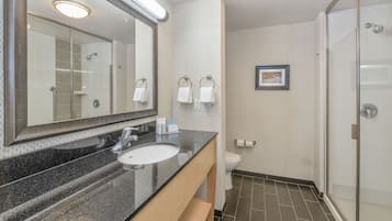 Ein Badezimmer mit einem großen Spiegel, einem Waschbecken, einer Toilette und einer Duschkabine.