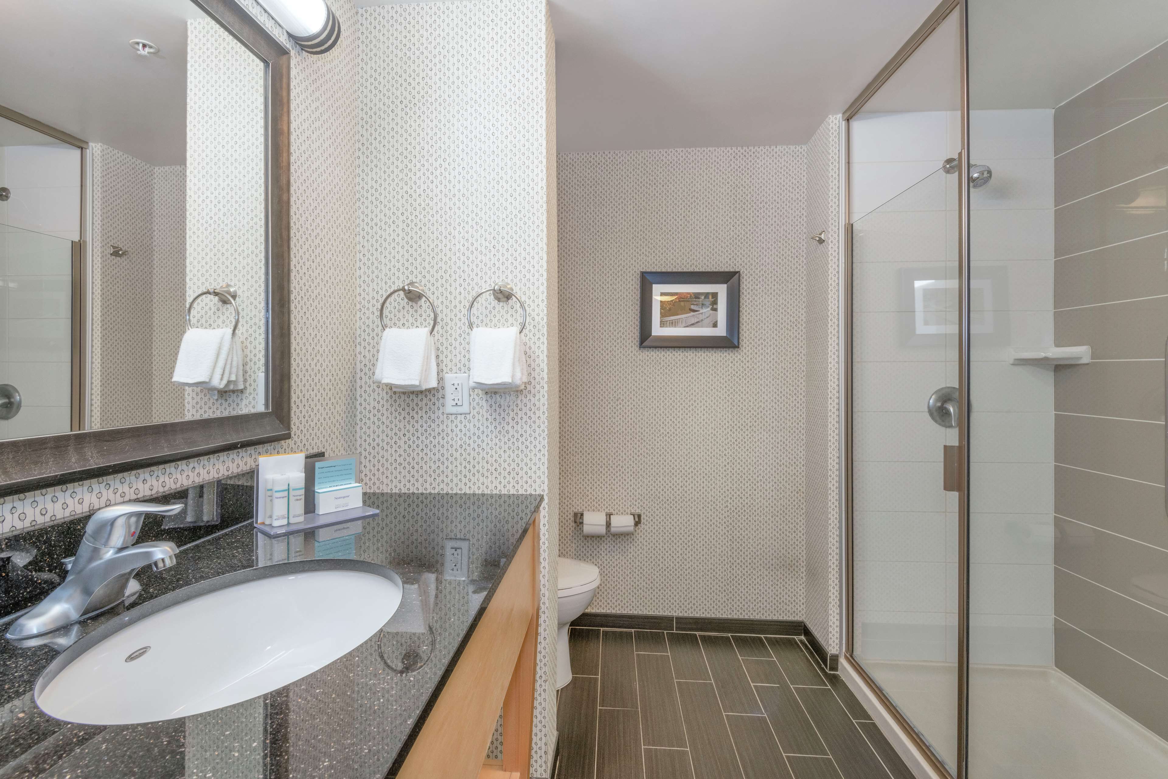 Une salle de bain moderne avec un grand miroir, un lavabo, des toilettes et un espace douche.