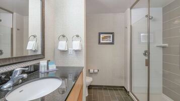 Une salle de bain moderne avec un grand miroir, un lavabo, des toilettes et un espace douche.