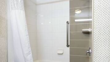 Un baño moderno con ducha, barra de apoyo y jabonera.