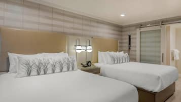 Habitación de hotel con dos camas, una mesita de noche con lámpara, un espejo y un armario con puerta corredera.