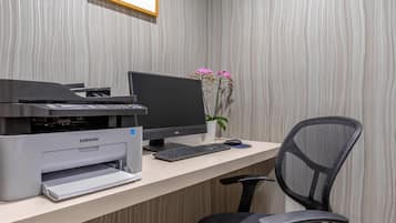 Un bureau moderne, équipé d’une imprimante, d’un écran, d’un clavier et d’une chaise.