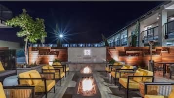 Un área de estar al aire libre con sillas amarillas y una chimenea.