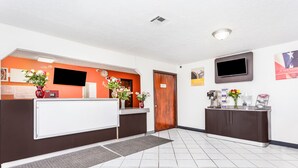 A reception area with a reception desk, a clock, a TV, and a coffee station. - Relax Inn by OYO Columbus OH I 70 (Columbus)