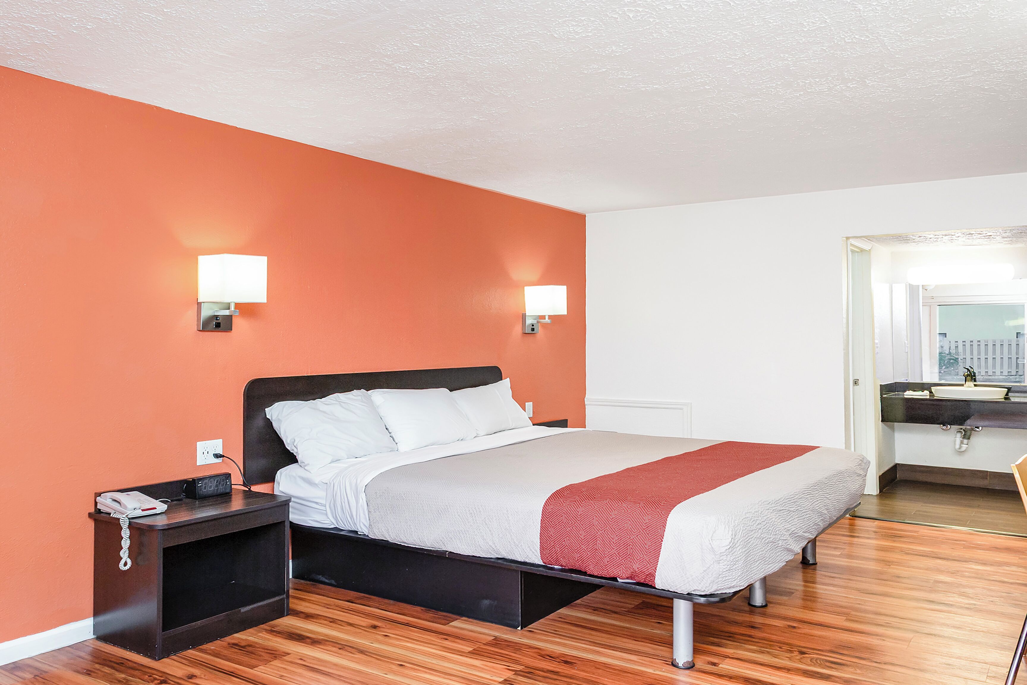 A hotel room with a bed, nightstand, and a bathroom visible through an open door.