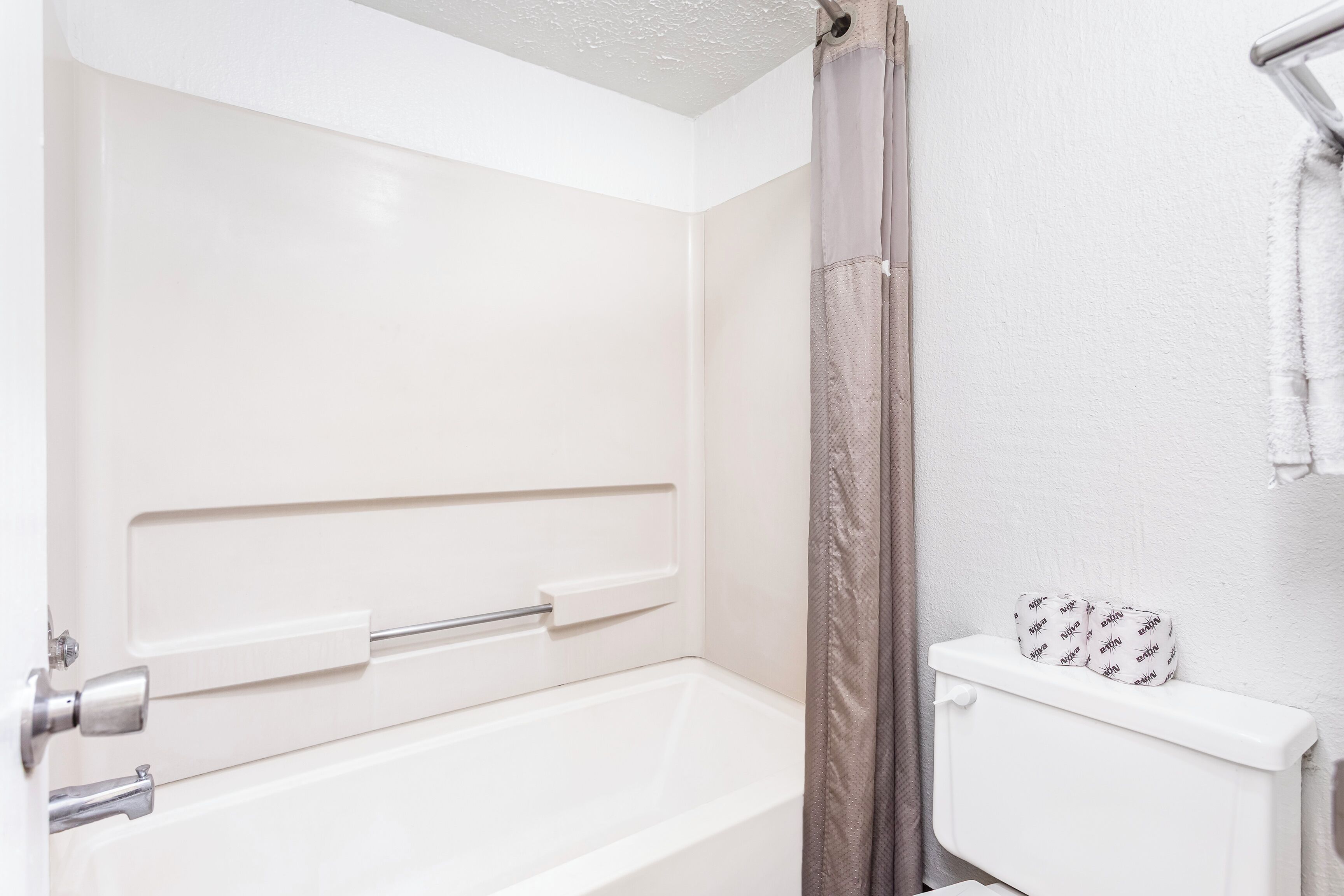 A bathroom with a white bathtub, a shower curtain, and a toilet with a white tank.