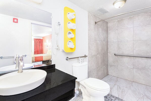 A bathroom with a white sink, black countertop, and a shower area with a glass door.