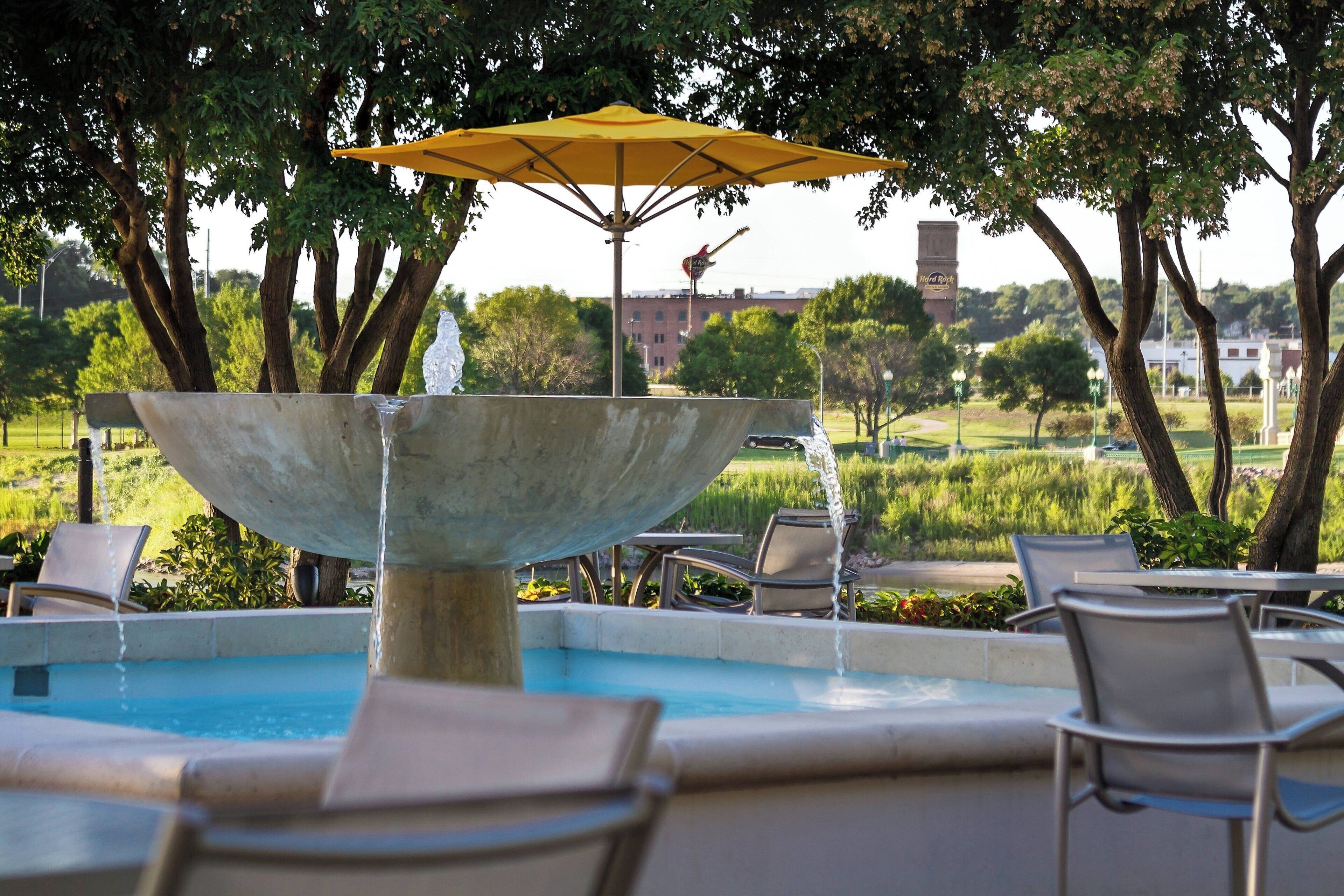 A pool area with a central water feature, lounge chairs, and an umbrella.