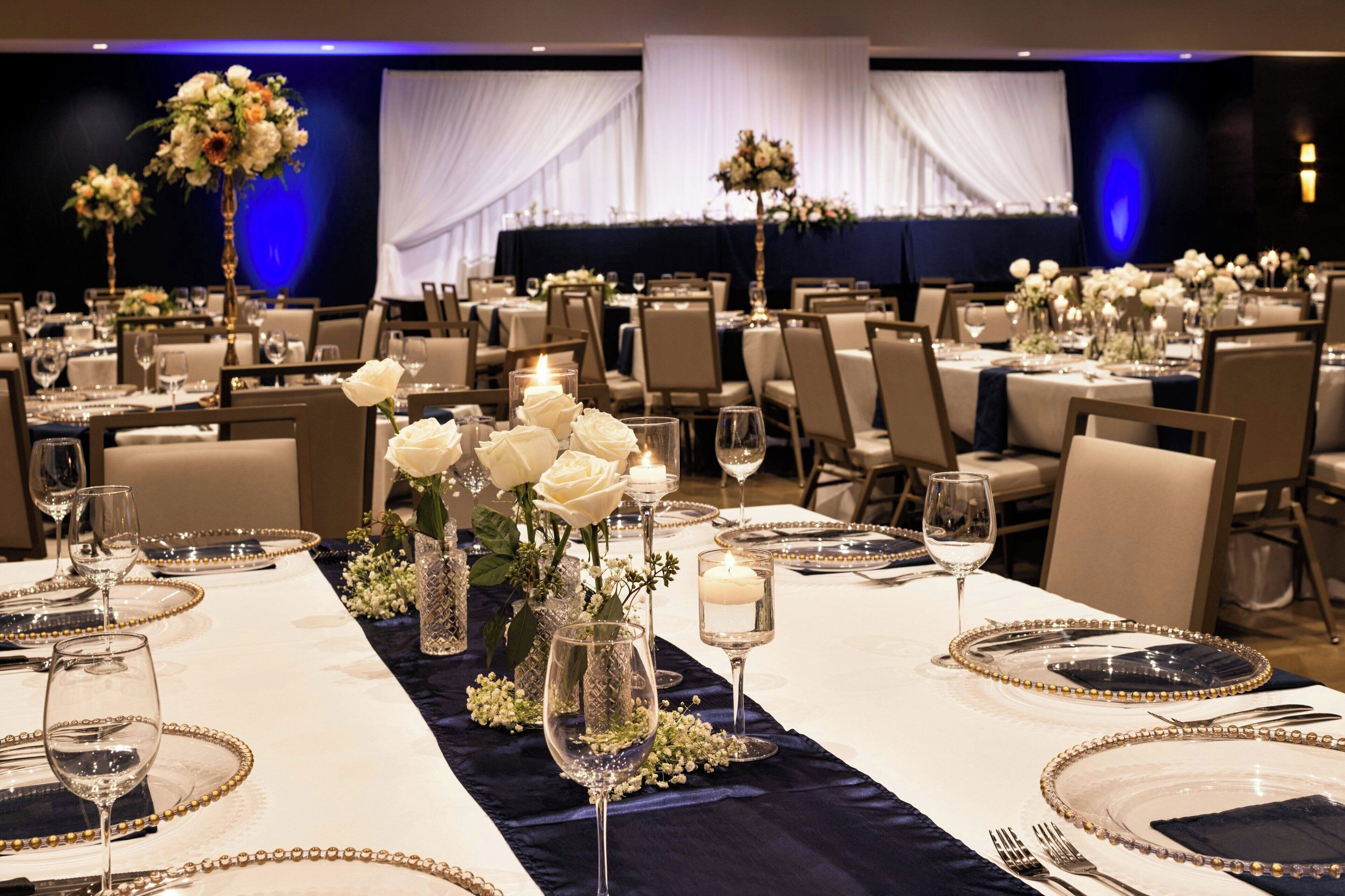A banquet hall with tables set for a formal event, featuring floral centerpieces and elegant table settings.