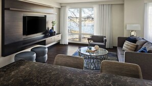 Una sala de estar moderna con televisor de pantalla plana, asientos cómodos, una mesa de centro y un ventanal con vistas.