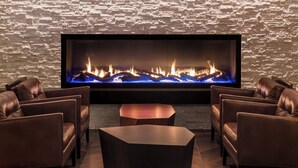 Una sala de estar moderna con sofás de cuero, una mesa de centro y un televisor de pantalla plana grande que muestra una chimenea.