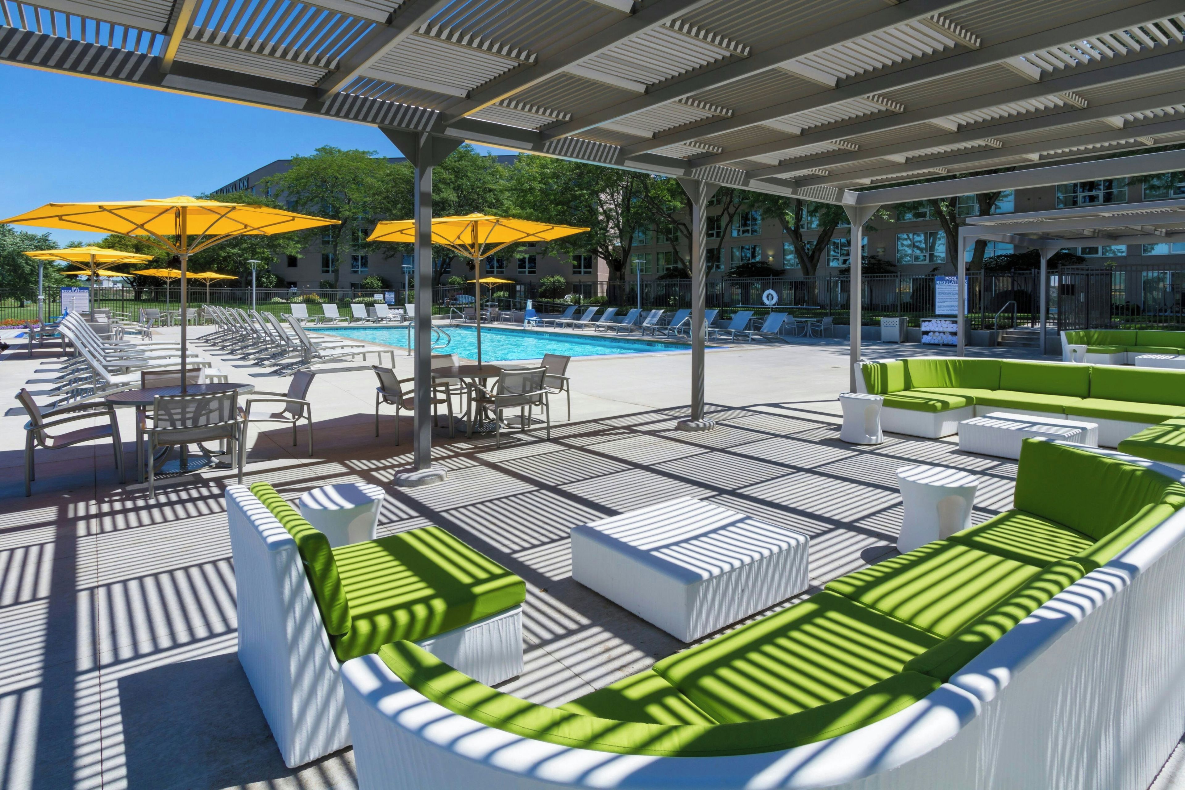 A poolside area with sun loungers, umbrellas, and a pool.