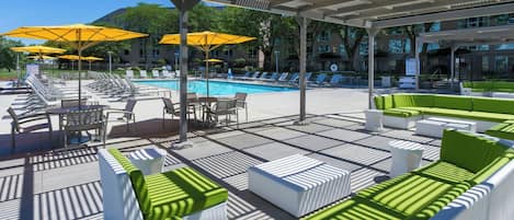 A poolside area with sun loungers, umbrellas, and a pool.