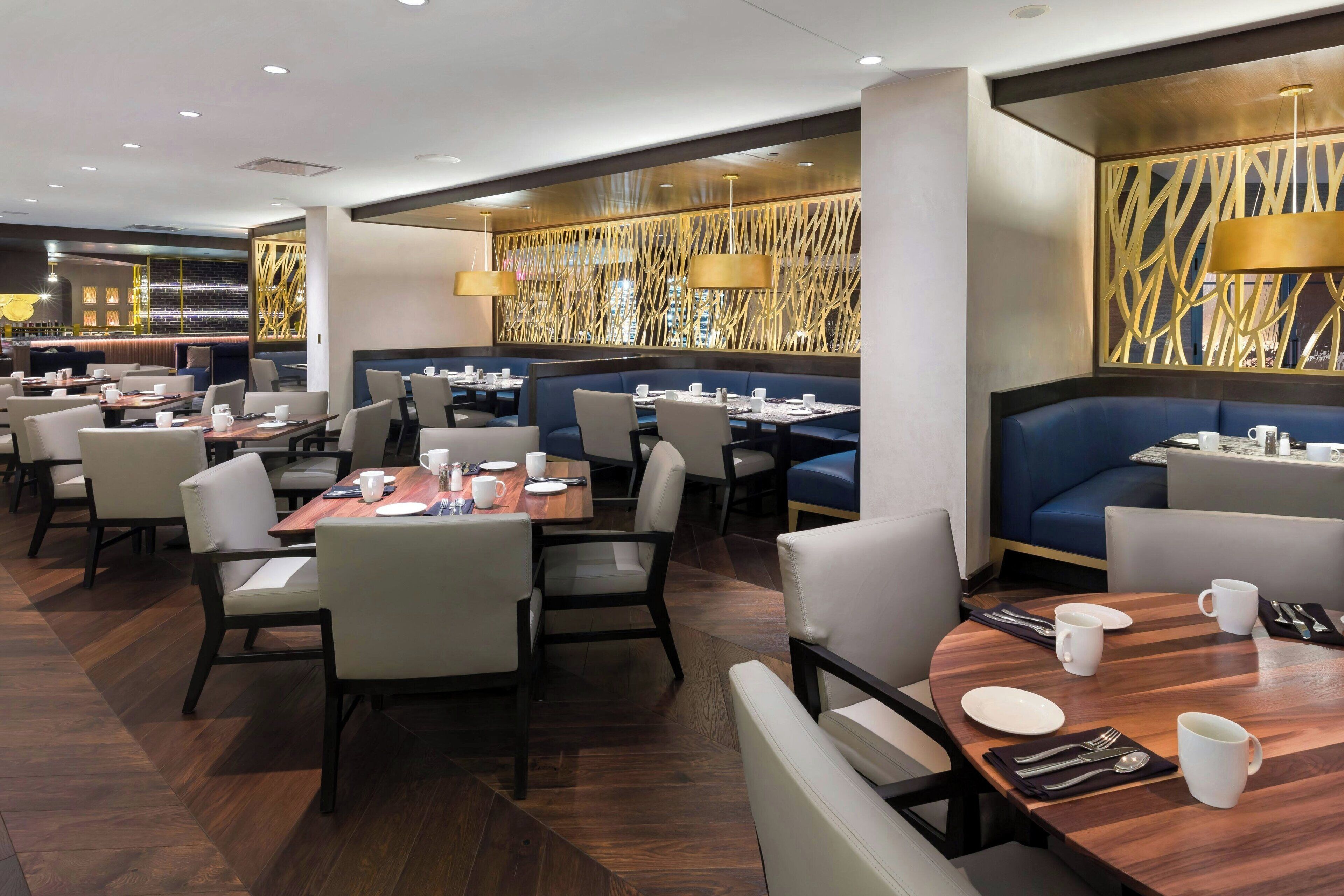 A modern restaurant with multiple dining areas, including booths and tables, and a decorative wall with a unique pattern.