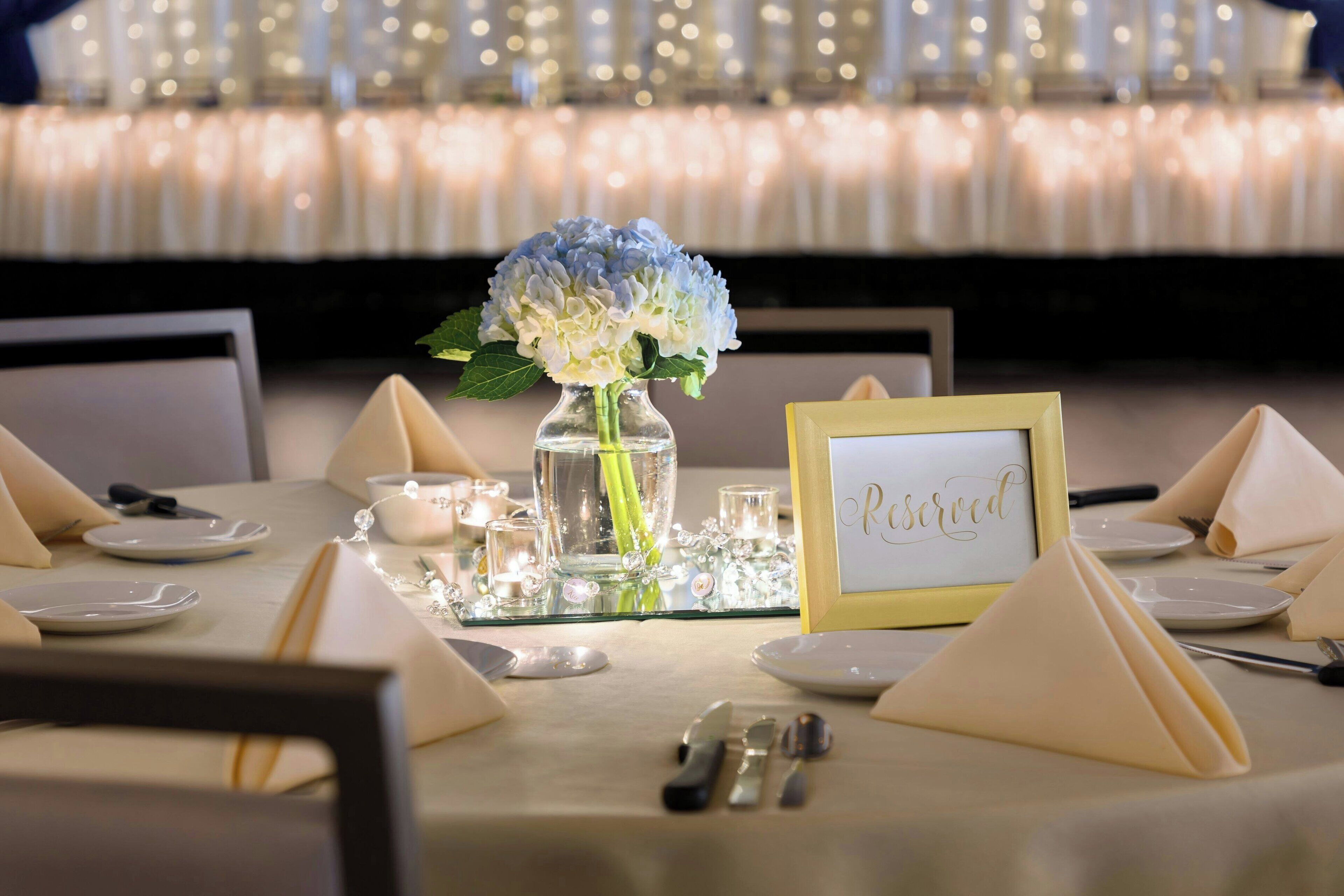 Une table dressée pour un repas, avec une pancarte indiquant « Réservé », un vase de fleurs et un chandelier.