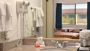 A hotel bathroom with a sink, a hairdryer, and a coffee maker.
