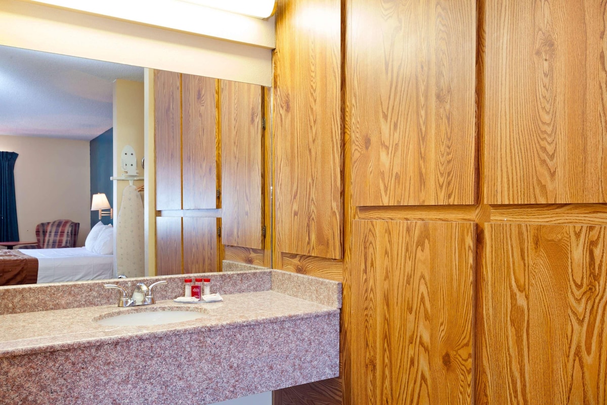 A hotel bathroom with wooden paneling, a granite countertop, a sink, and a mirror.