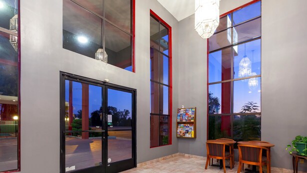 A hotel lobby with large windows, a reception desk, and a seating area with two wooden chairs.