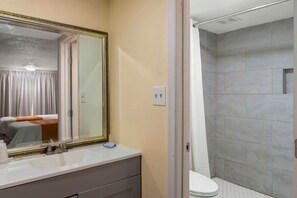 Un baño con un espejo grande, un lavamanos y una zona de ducha.