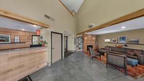 A reception area with a wooden reception desk, a sofa, and a fireplace. - Country Inn & Suites by Radisson, Fargo, ND (Fargo)